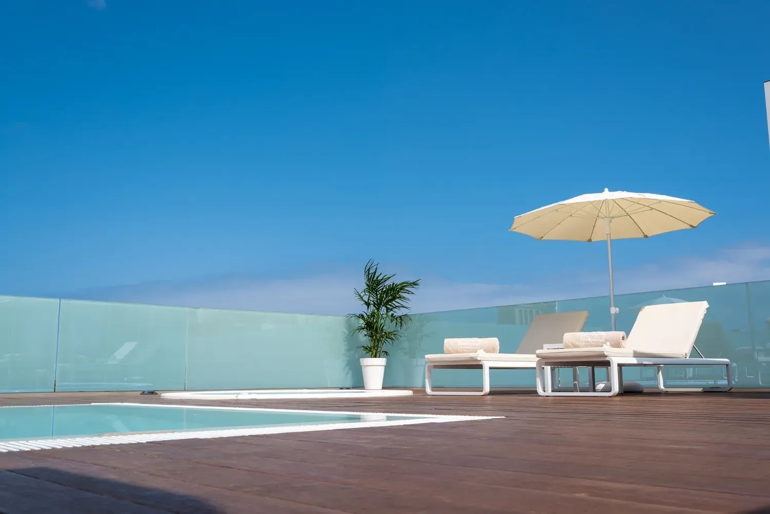 a swimming pool with chairs and an umbrella on the deck