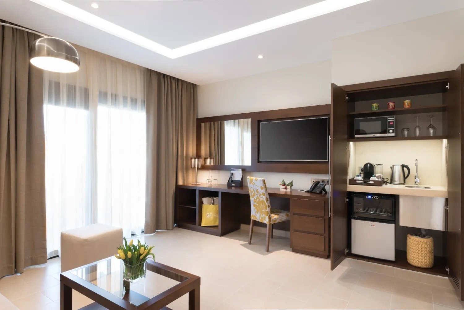 a hotel room with a desk a chair and a flat screen tv