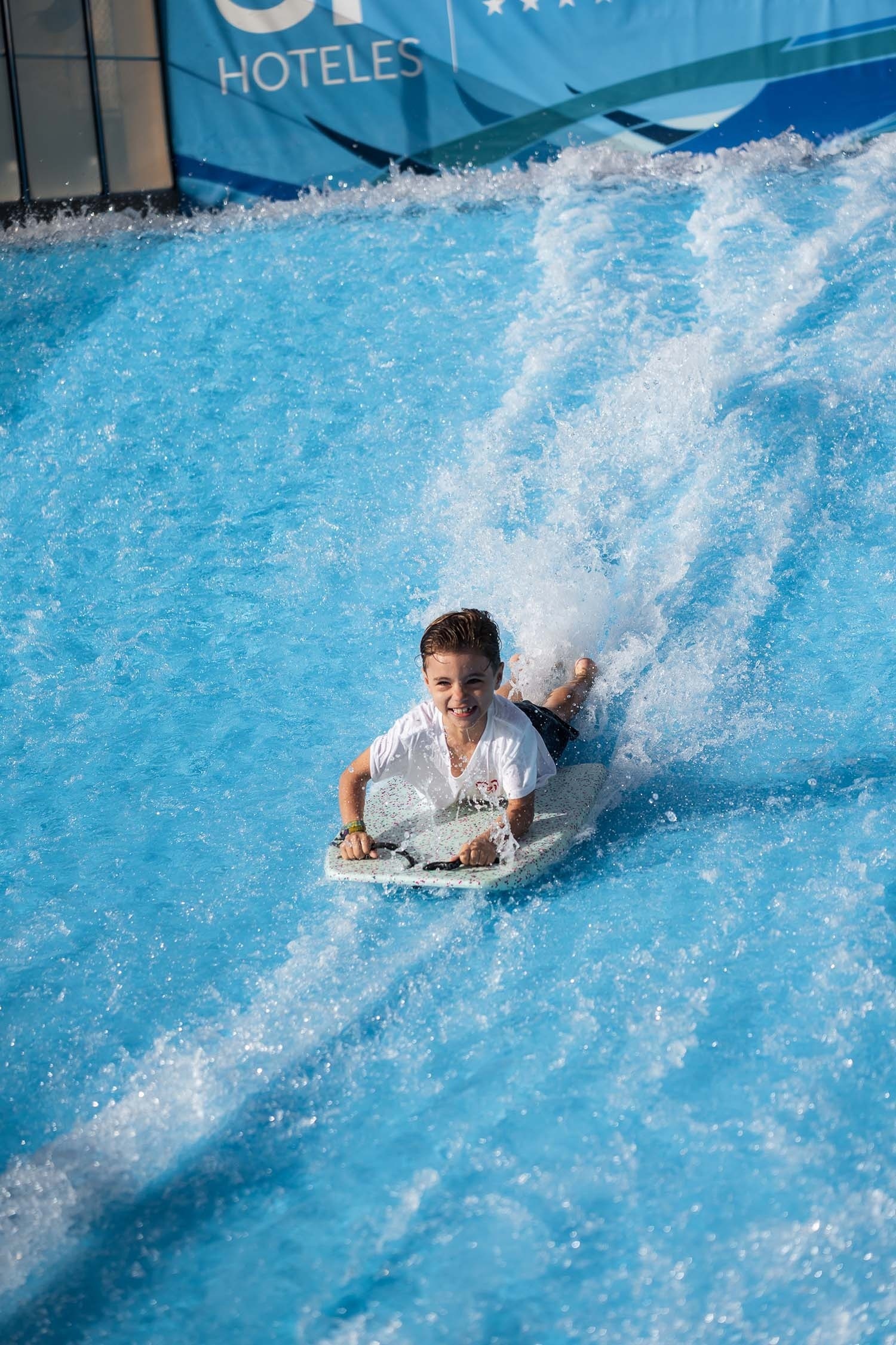a boy on a boogie board in front of a hoteles sign