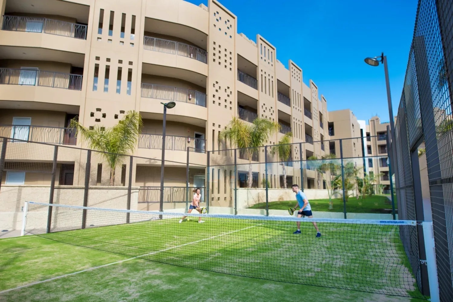 two people are playing tennis in front of a large building