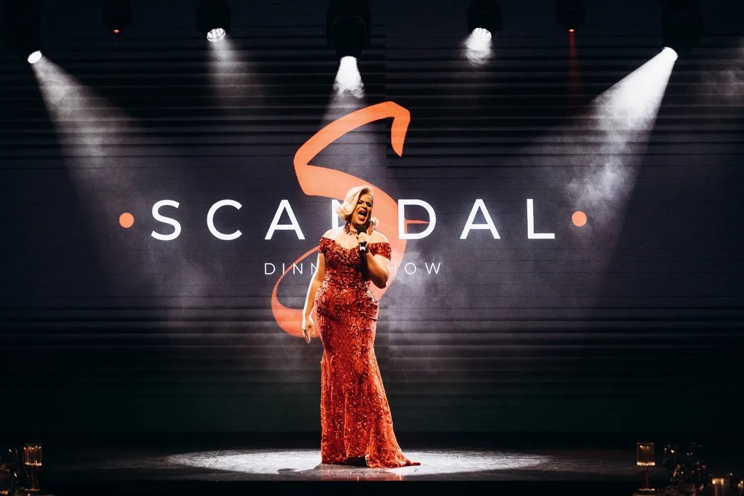 a man in a white jacket is surrounded by women in white dresses with red polka dots