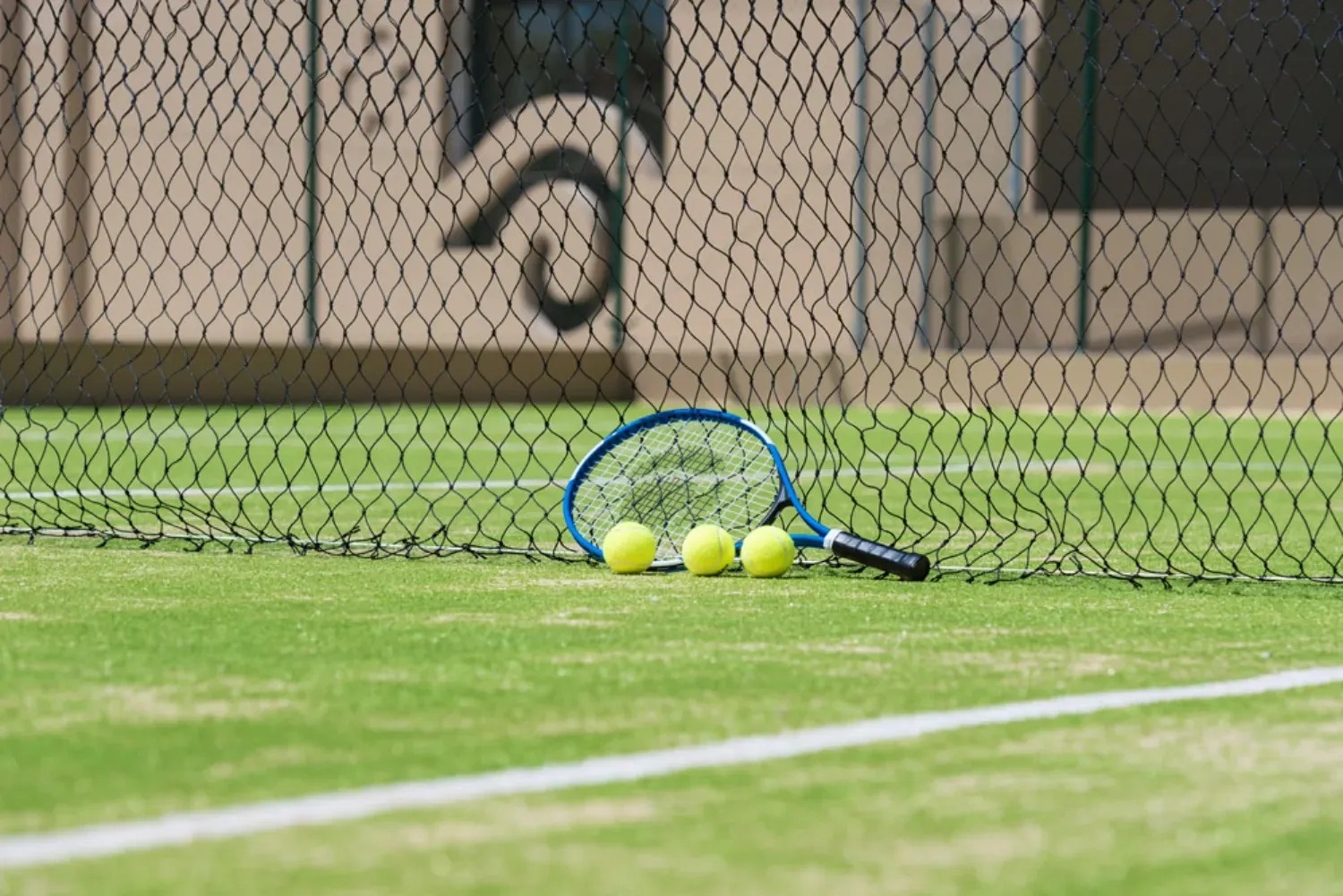 una raqueta de tenis y tres pelotas de tenis en una cancha de tenis