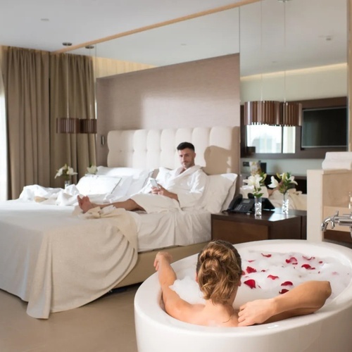 una mujer se relaja en una bañera junto a un hombre en una cama