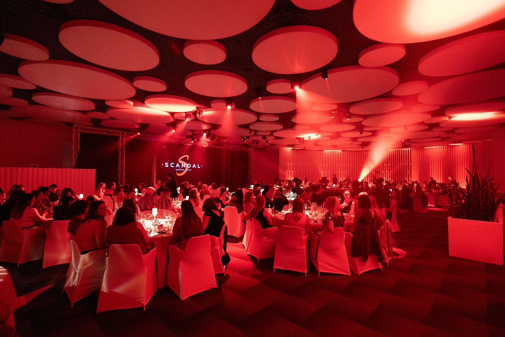 un grupo de hombres y mujeres en vestidos blancos con lunares rojos están actuando en un escenario