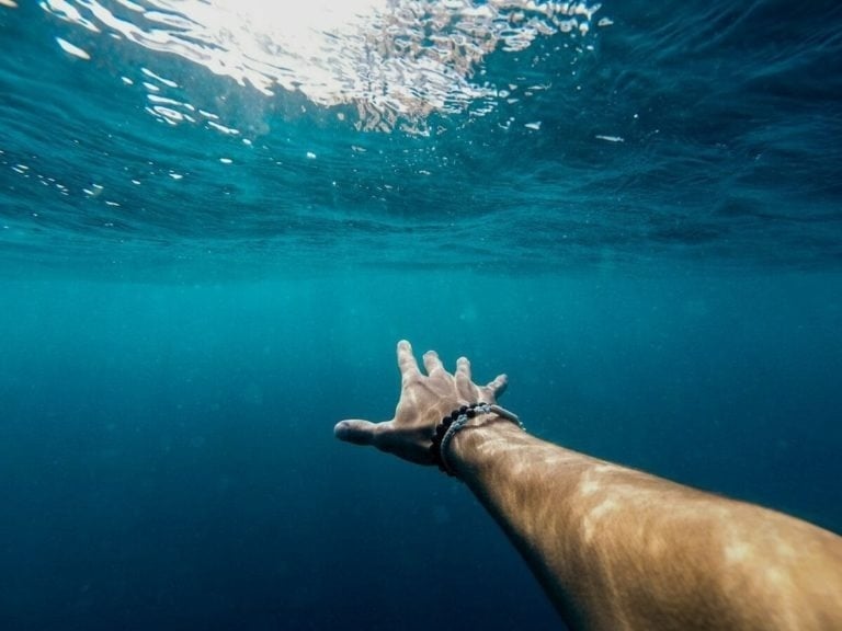 a person 's hand is reaching out into the ocean