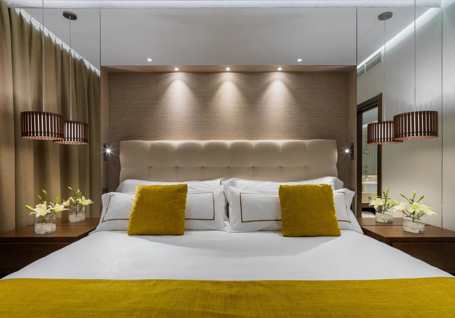 a bed with yellow pillows and white sheets in a hotel room