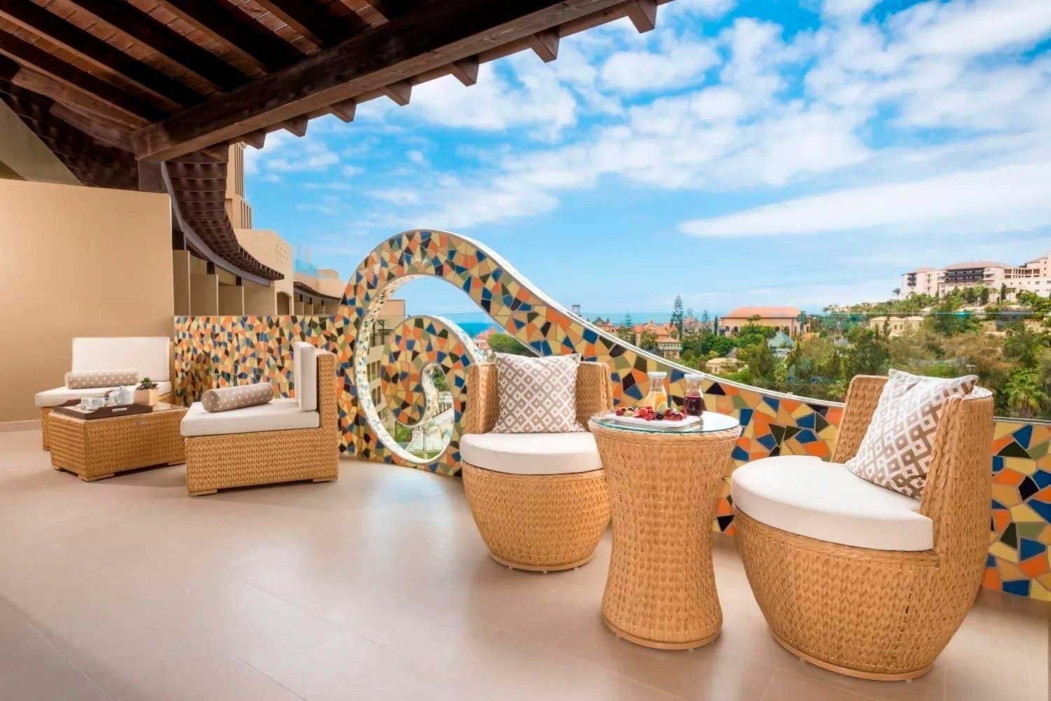 a balcony with chairs and a table with a view of the ocean