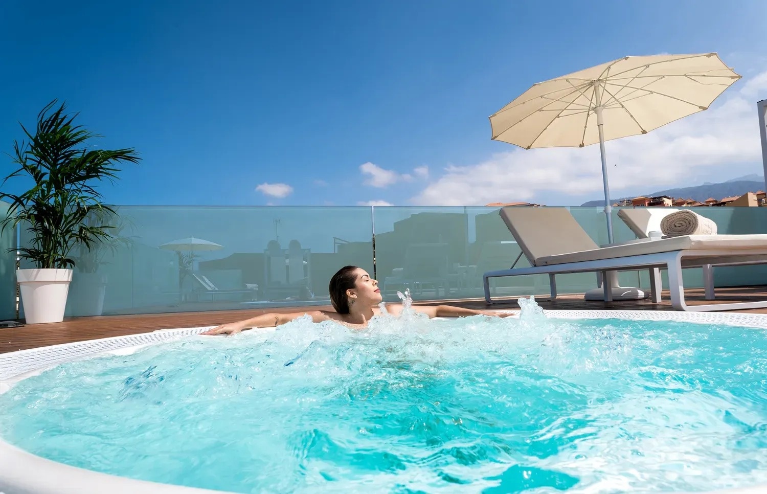 a woman is laying in a hot tub with an umbrella in the background