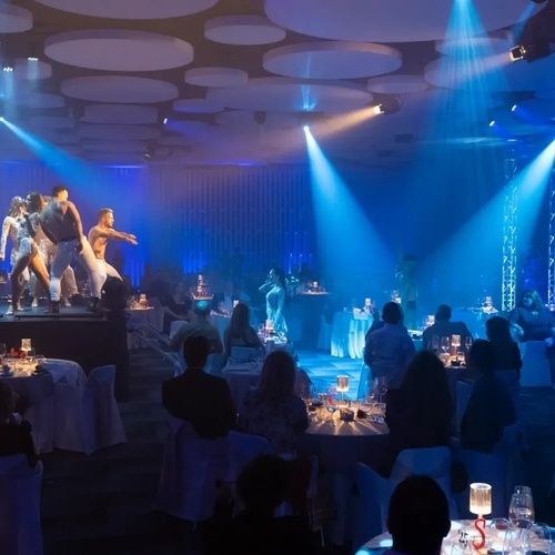 un grupo de bailarines actúan en un escenario en una habitación llena de gente