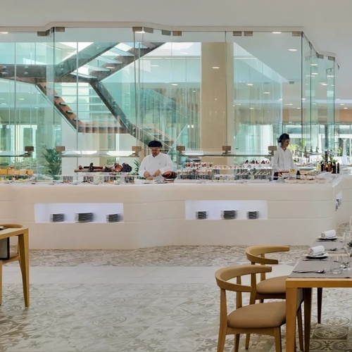 dos cocineros preparan comida en un restaurante con mesas y sillas