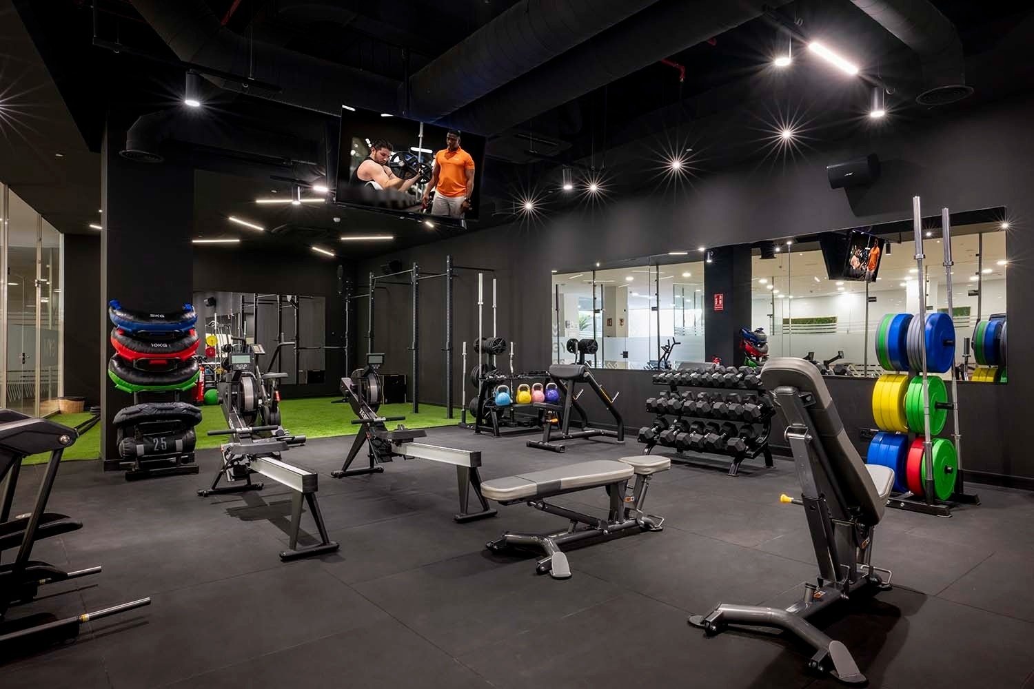 un gimnasio con muchos aparatos y una pantalla de televisión
