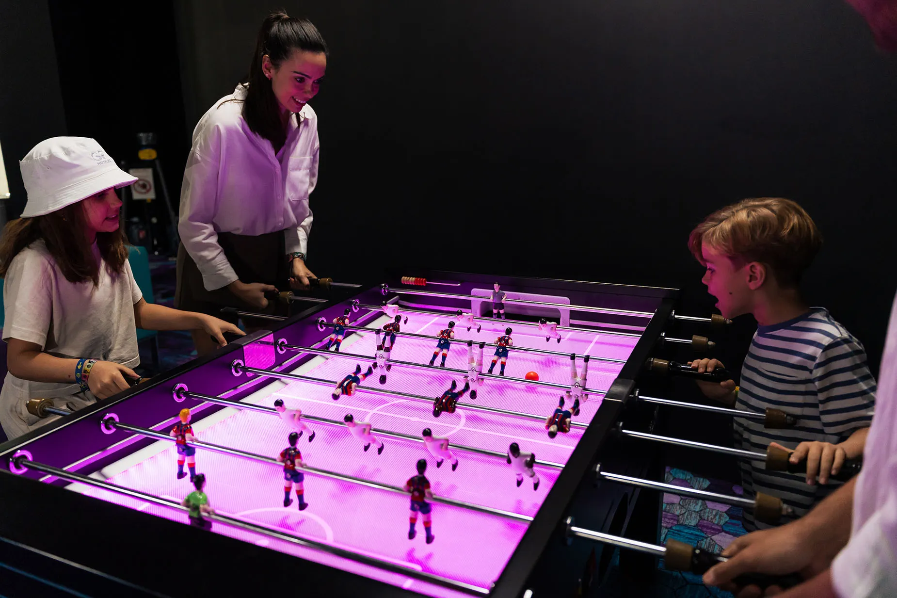 Niños jugando futbolín iluminado en hotel. GF: Victoria