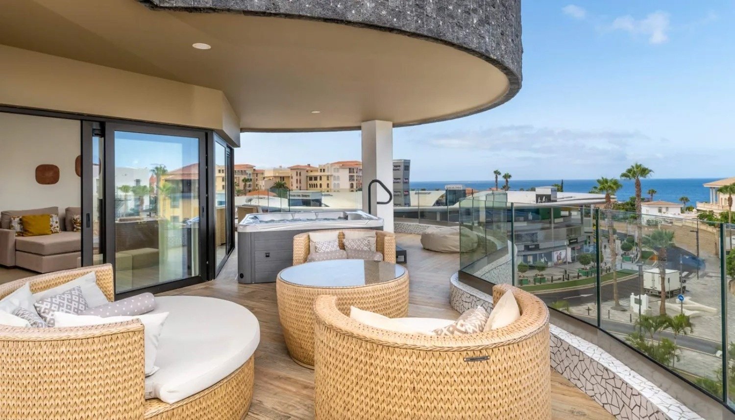 a balcony with wicker furniture and a hot tub
