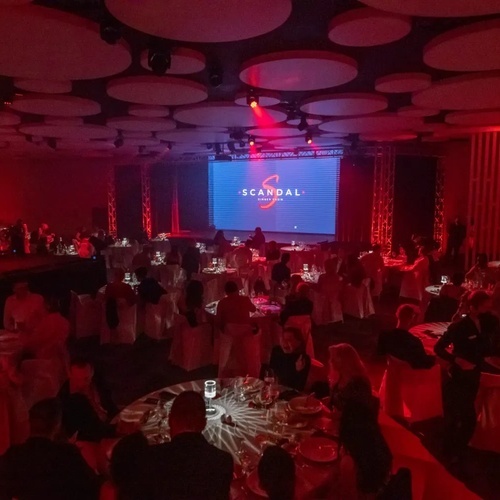 una habitación llena de mesas y sillas con una pantalla que dice 