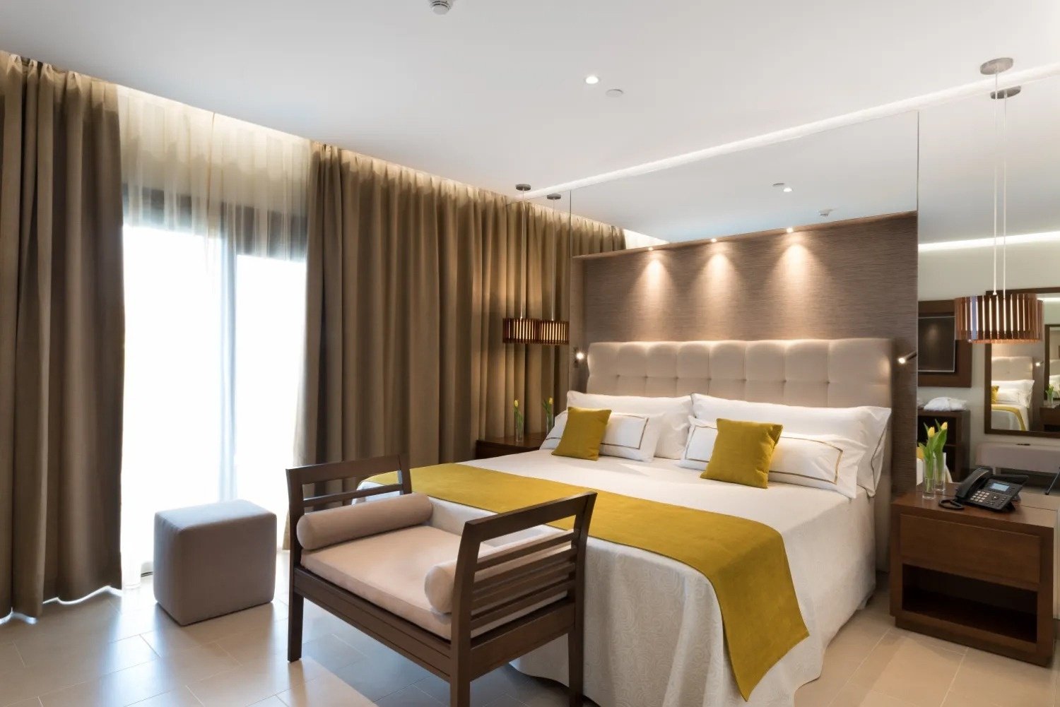 a hotel room with a large bed and yellow pillows