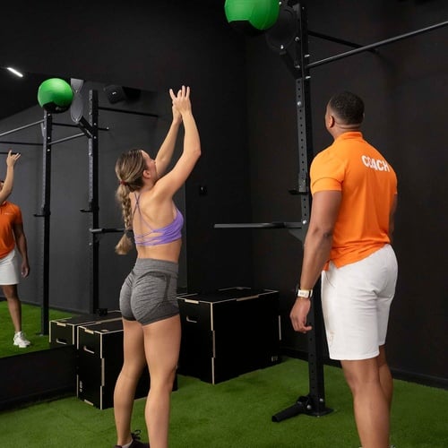 un hombre con una camisa naranja con la palabra coach en él