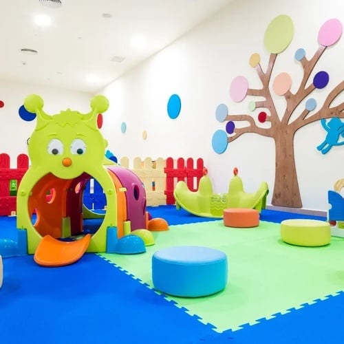 un área de juegos para niños con un árbol en la pared