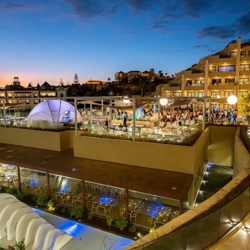 un grupo de personas se sienta en una terraza de un hotel al atardecer