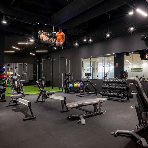 un gimnasio con muchos aparatos y una pantalla de televisión