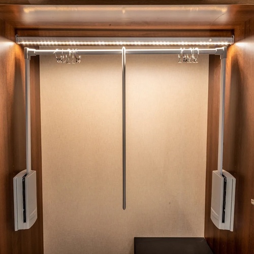 a closet with clothes hanging on a rack and a light on