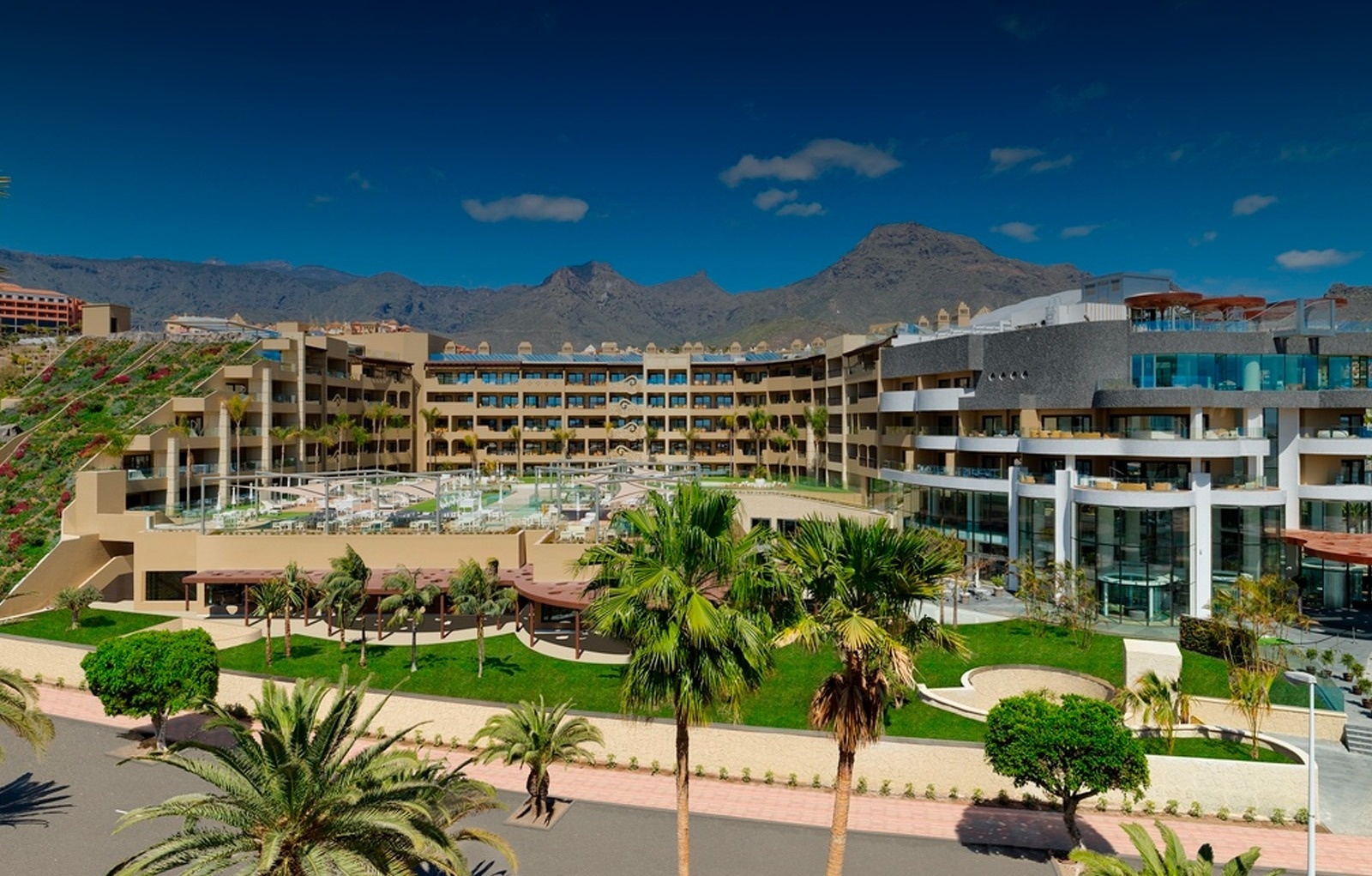 un gran hotel con palmeras y montañas en el fondo