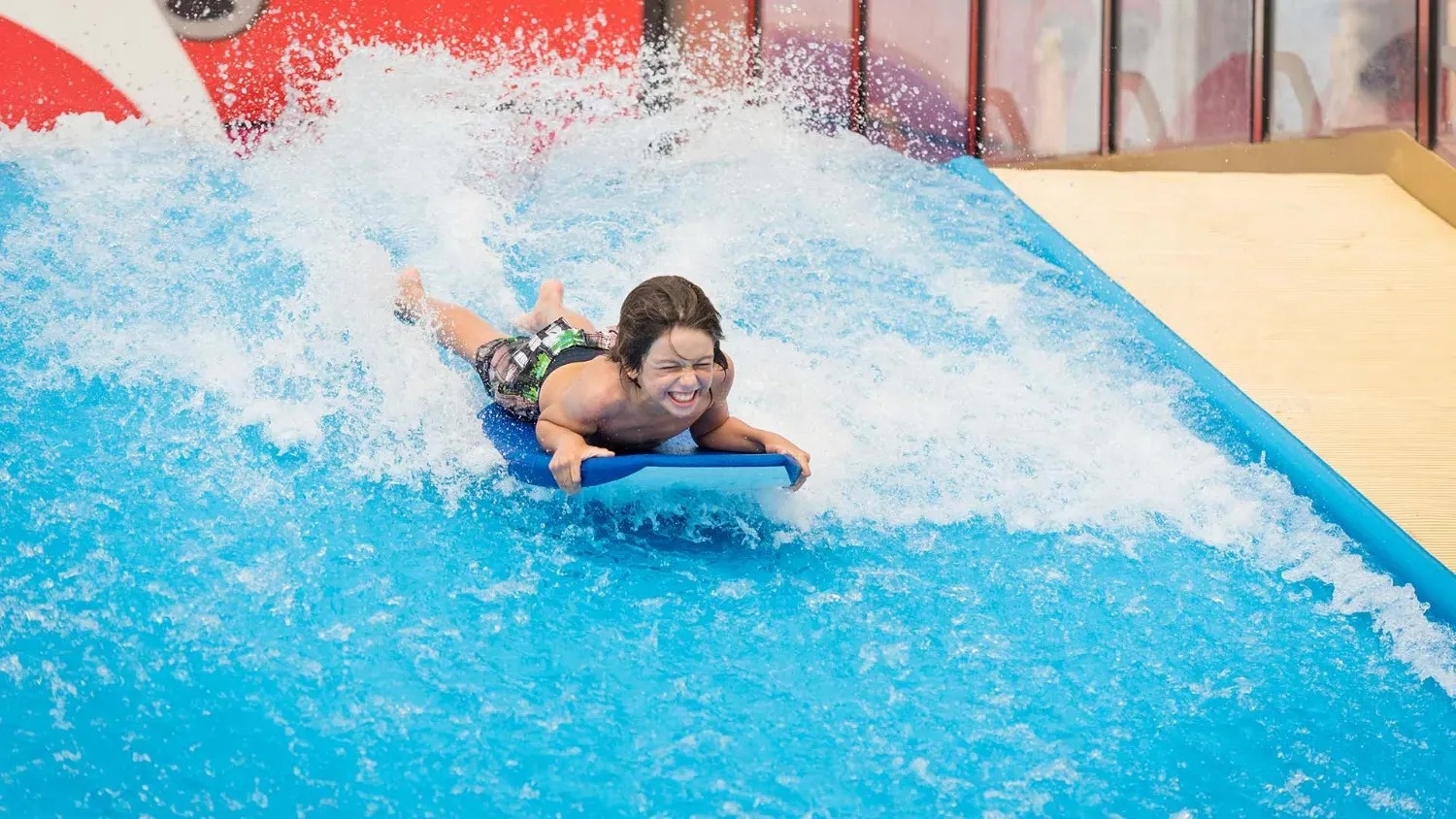 a young boy is riding a wave on a boogie board