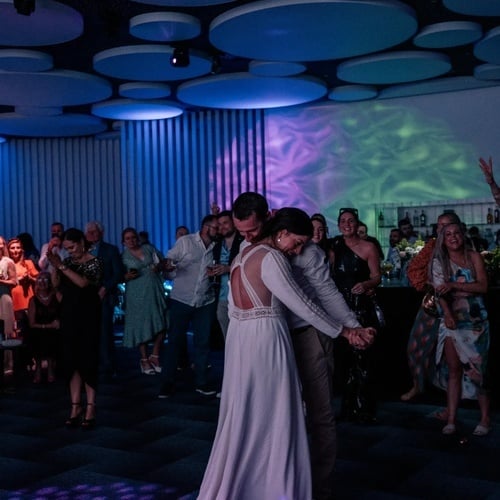 una novia y un novio bailan en una habitación llena de gente