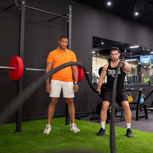 dos hombres en un gimnasio uno de ellos lleva una camiseta naranja que dice everlast