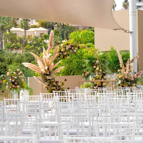una fila de sillas blancas están dispuestas para una ceremonia de boda al aire libre