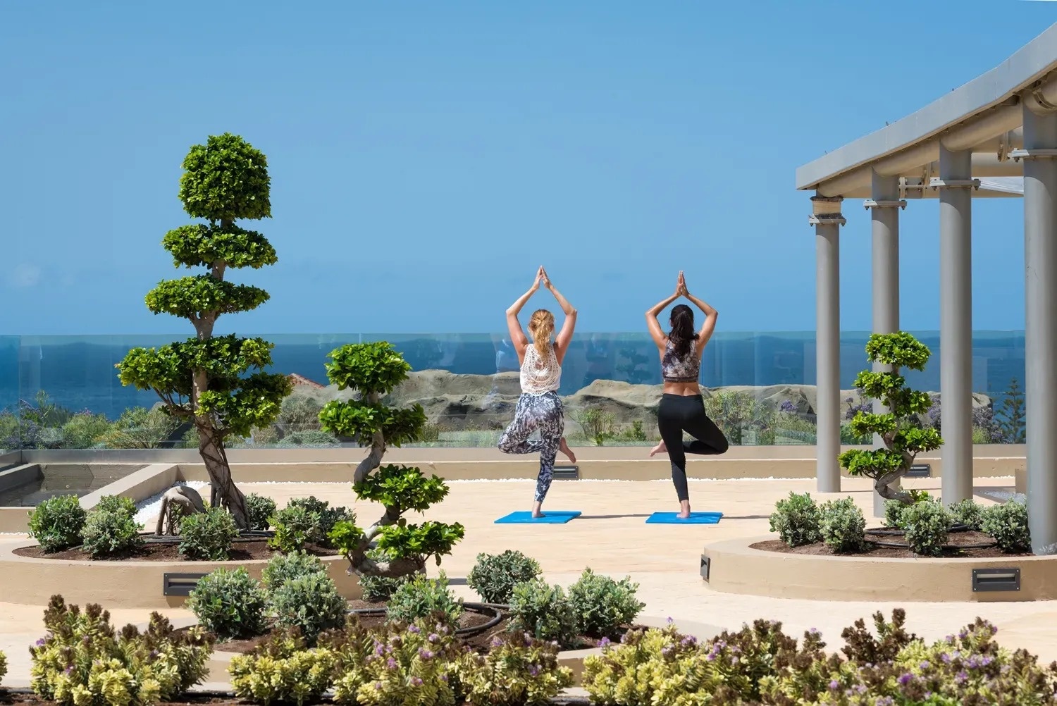 dos mujeres están practicando yoga en un patio al aire libre
