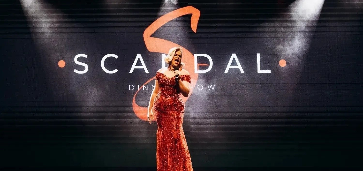 a woman in a red dress sings in front of a sign that says scandal