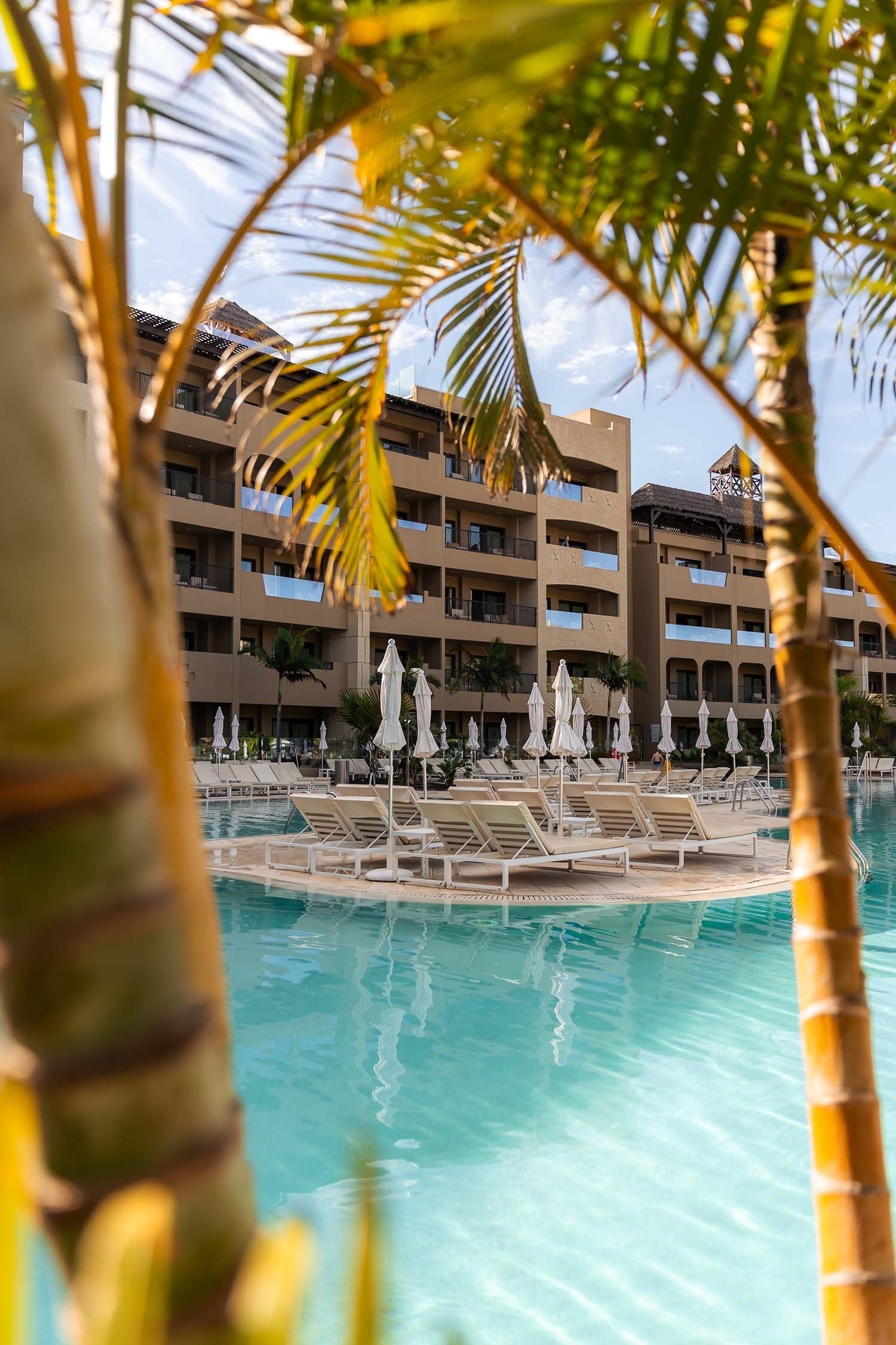 a large swimming pool with chairs and umbrellas in front of a hotel