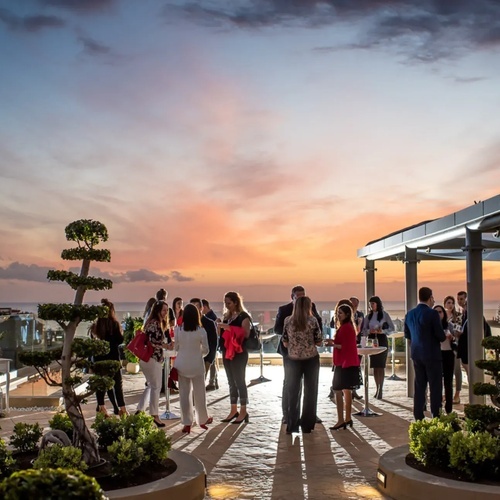 un grupo de personas se reúnen en una terraza al atardecer
