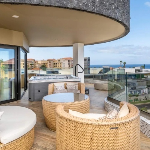 un balcón con muebles de mimbre y una bañera de hidromasaje