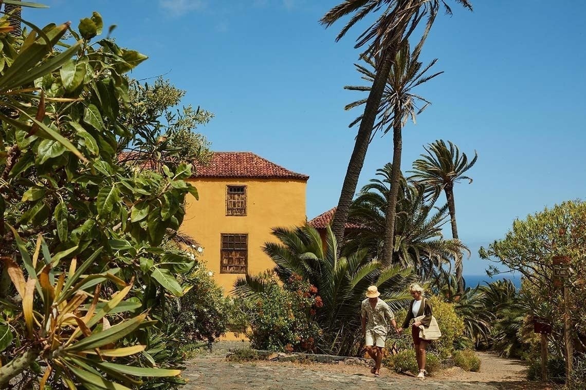 two people walking in front of a yellow building