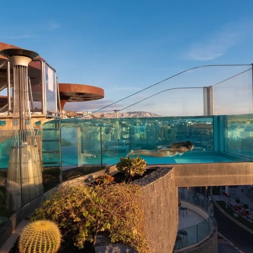 una mujer nada en una piscina transparente en la azotea de un edificio