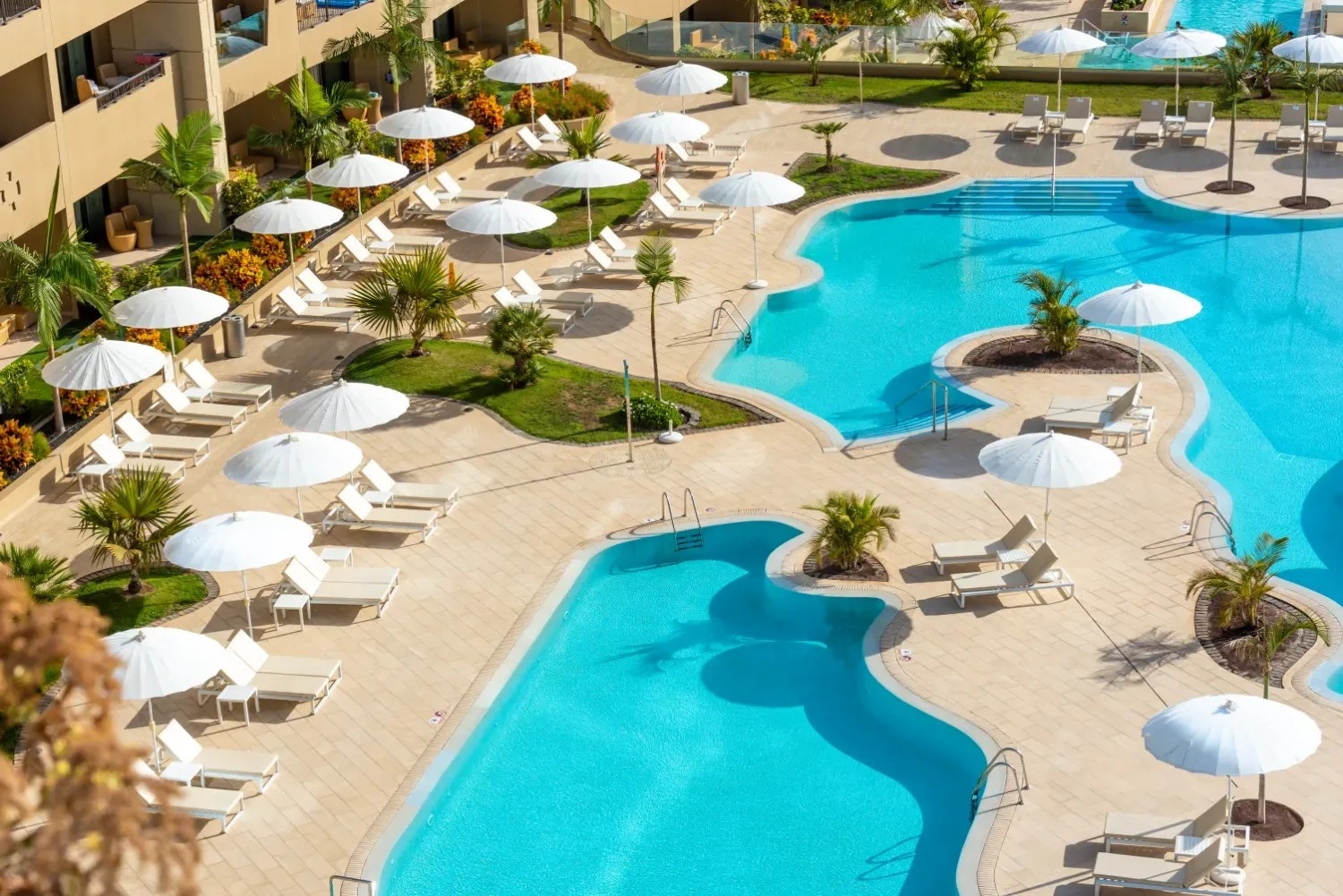 a large swimming pool surrounded by chairs and umbrellas