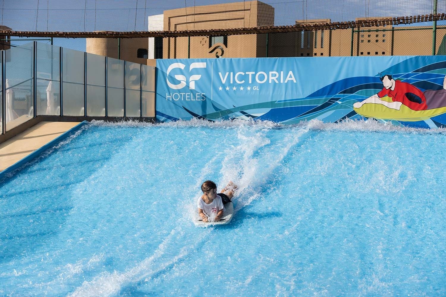 a person riding a wave in front of a sign that says victoria