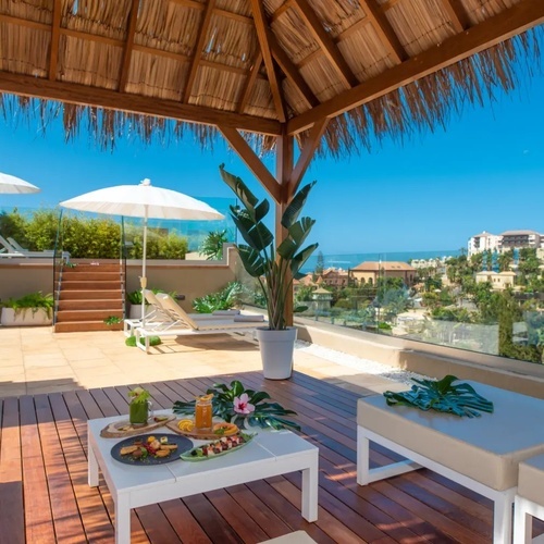 un patio con una mesa y sillas y un techo de paja