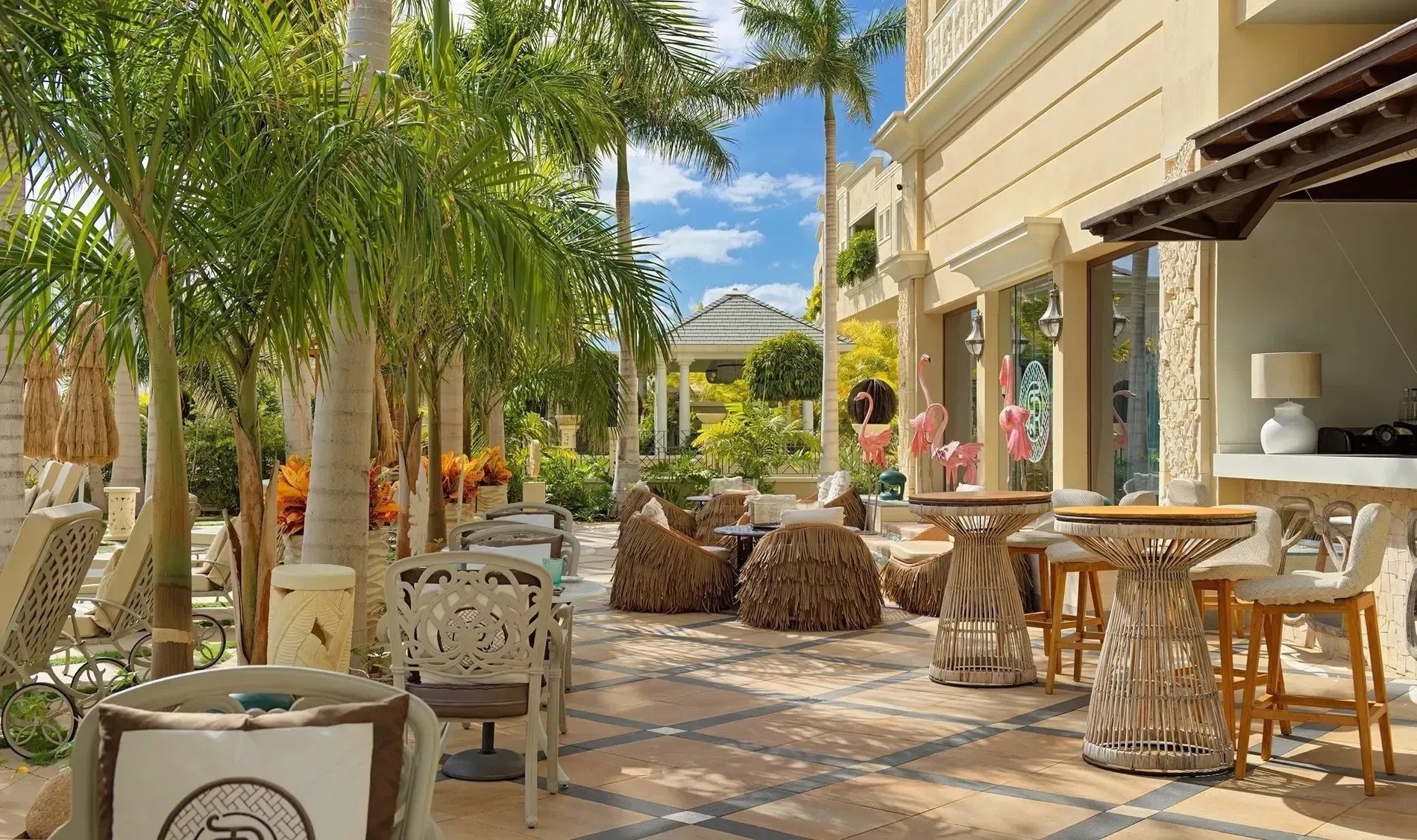 a patio area with tables and chairs and flamingos in the background