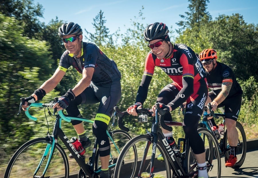 un grupo de ciclistas están en una carretera y uno de ellos lleva una camiseta de bmc