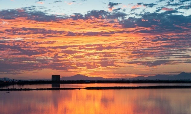 una puesta de sol sobre un lago con montañas al fondo