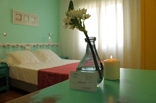 a hotel room with a vase of flowers and a candle