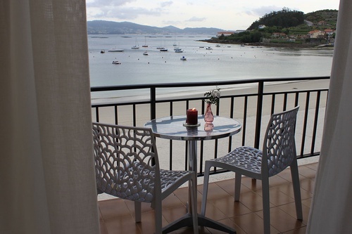 a table with a candle on it sits on a balcony overlooking the ocean