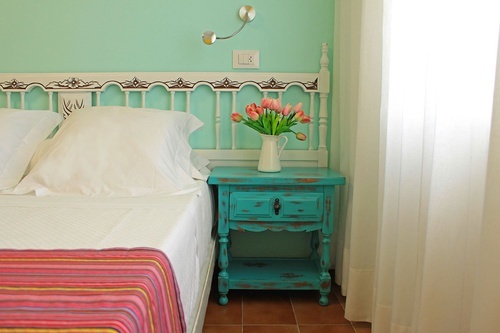 a bedroom with a bed and a nightstand with a vase of flowers on it