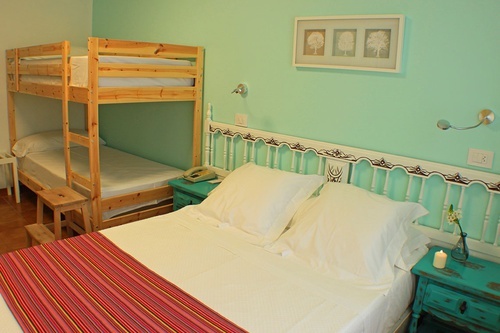 a bedroom with a bunk bed and a bed with white sheets
