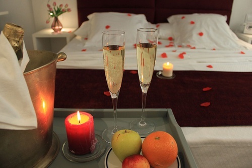 two glasses of champagne sit on a tray with fruit and candles