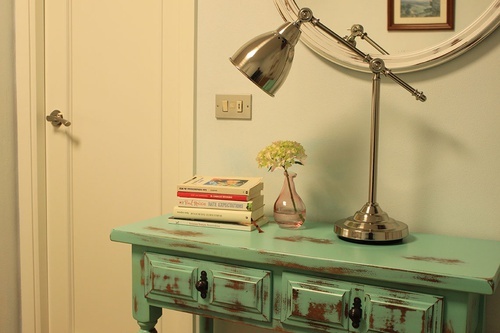 a stack of books sits on a table next to a lamp