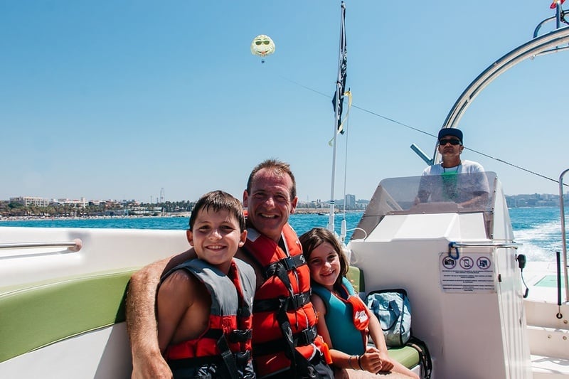 un hombre y dos niños están sentados en un bote en el océano