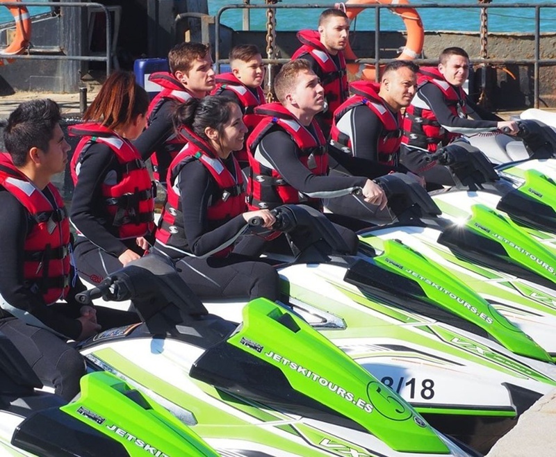 un grupo de personas están sentadas en jetski verdes y blancas